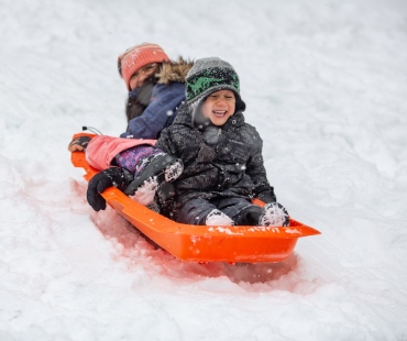 2 children sliding down hill on sled 2 children sliding down hill on sled