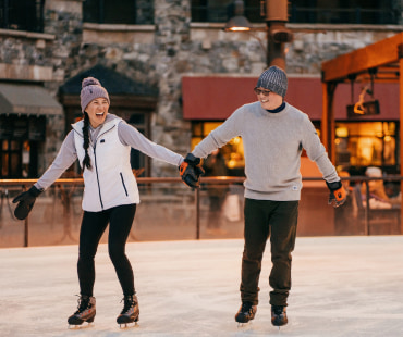 couple holding hands ice skating at Northstars outdoor rink couple holding hands ice skating at Northstars outdoor rink