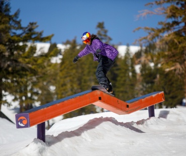 Snowboarder hitting rail at terrain park Snowboarder hitting rail at terrain park