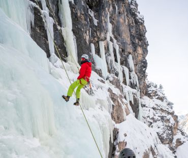 person ice climbing up frozen waterfall person ice climbing up frozen waterfall