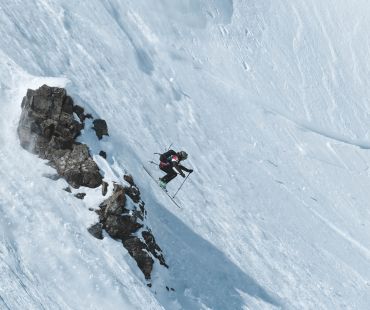 Experienced skier launching off mountain face in backcountry Experienced skier launching off mountain face in backcountry