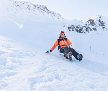 Person sledding down snowy trails Person sledding down snowy trails