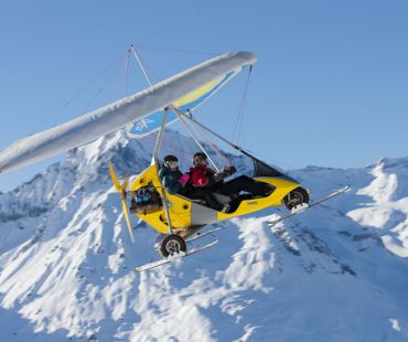 Microlight flying through the snowy valley Microlight flying through the snowy valley