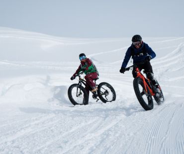 Pair of people fat biking on deep snowy trails Pair of people fat biking on deep snowy trails