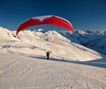 Person parachuting high up in the Alps Person parachuting high up in the Alps
