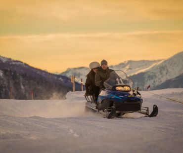 People at sunset riding on trails in snowmobile People at sunset riding on trails in snowmobile