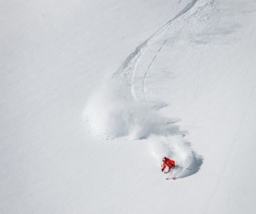 Skier carving through deep snow bowl Skier carving through deep snow bowl