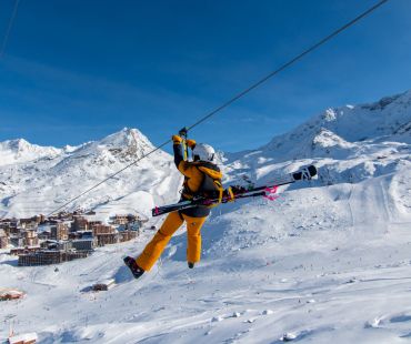Person flying down zipline with snowy mountain scenery Person flying down zipline with snowy mountain scenery