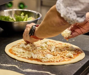 Chef sprinkling cheese on pizza dough Chef sprinkling cheese on pizza dough