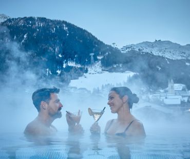 Couple enjoying cocktail in warm hot baths Couple enjoying cocktail in warm hot baths