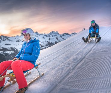 People sledding at sunset People sledding at sunset