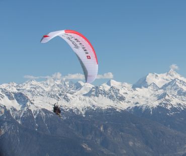 Person paragliding above the mountain peaks Person paragliding above the mountain peaks