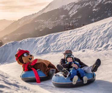 People and mascot tubing on snow trails People and mascot tubing on snow trails