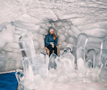 Person sitting on ice throne inside cave Person sitting on ice throne inside cave
